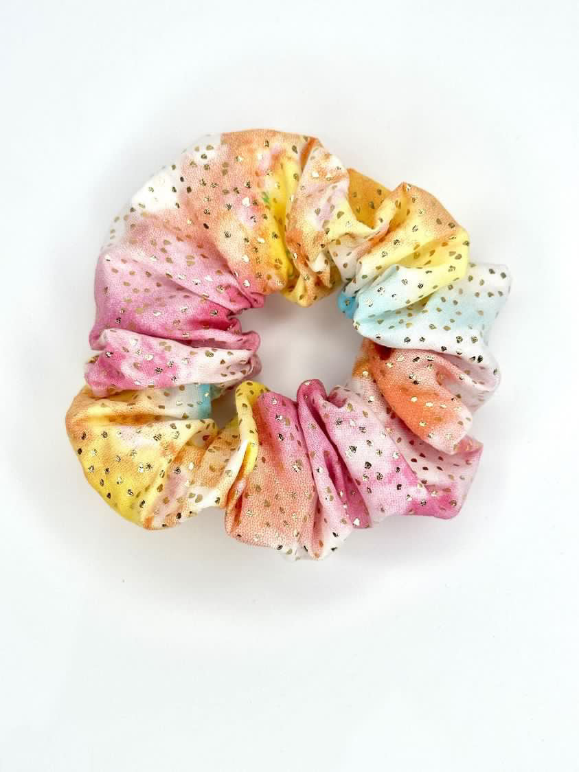 A top view angle of the scrunchie showing how the gold flecks catch the light and have a shine standing out from the tie-dye background colour of the fabric